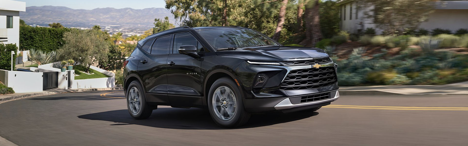 2025 Chevrolet Blazer in black driving along a winding residential road