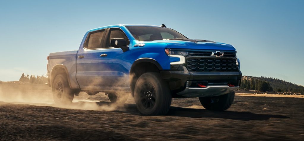 2026 Chevrolet Silverado off-road pickup truck in motion on a rugged dirt surface, showcasing performance, suspension, and aggressive front design.