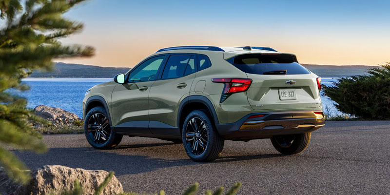 2026 Chevrolet Trax green SUV rear view parked against a scenic landscape, highlighting its stylish design and modern compact appeal.