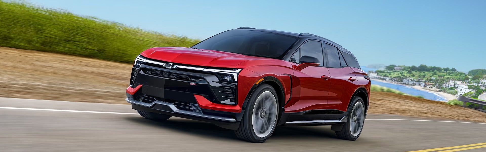 Red 2026 Chevrolet Blazer driving through scenic road showcasing performance and build.